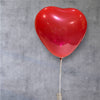 Red heart-shaped balloon against a gray concrete wall