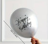 Gray balloon with 'Happy Birthday' text held by a hand against a white background